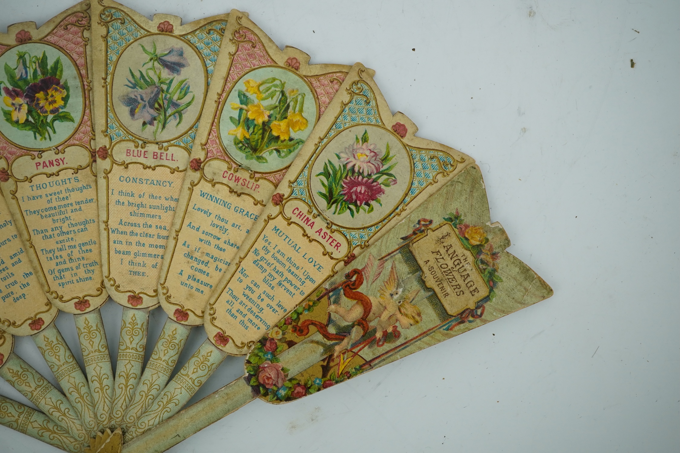 Three novelty fans with a mixed Brussels lace fan and black lace fan, a small language of love in flowers fan, a paper windmill advertising French Café fan, a carved cream Bakelite fan, a black and gilt, lace and sequin